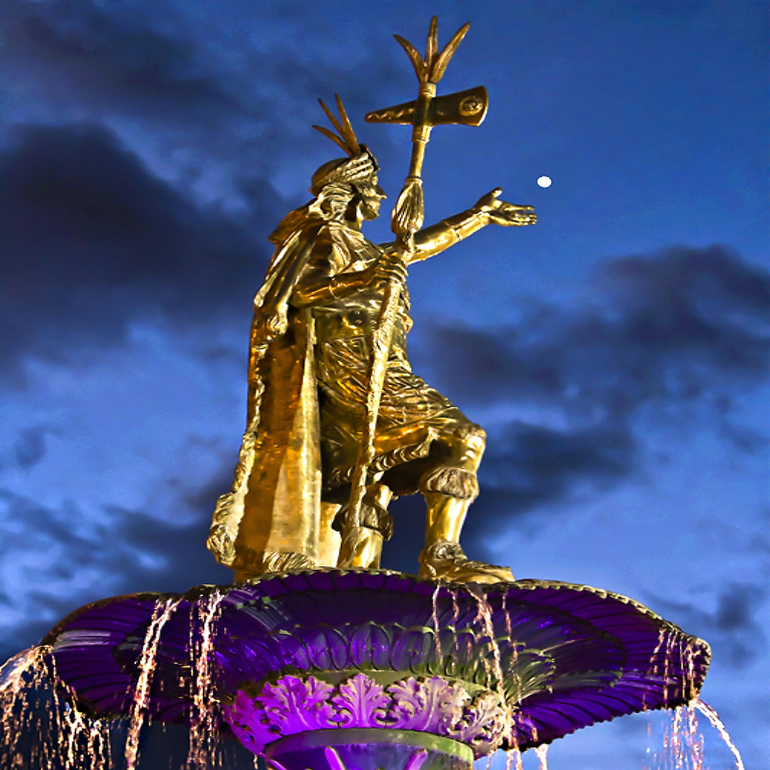 Golden Inca statue and fountain at dusk in Cusco